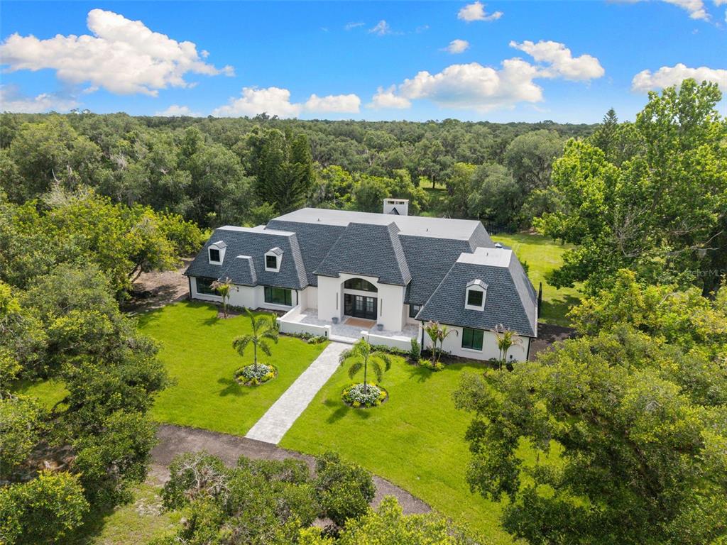 An aerial view shows a white two-story house with a dark shingled roof and dormers — 7351 IGUANA DRIVE, SARASOTA, FL