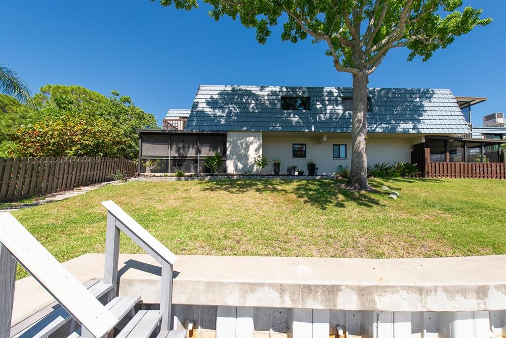 A two-story house with a blue mansard roof sits behind a grassy lawn and fence — 9476 TRADEWINDS AVENUE UNIT 9476, SEMINOLE, FL