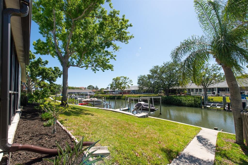 A grassy backyard overlooks a narrow canal with boat docks and surrounding residential homes — 9476 TRADEWINDS AVENUE UNIT 9476, SEMINOLE, FL