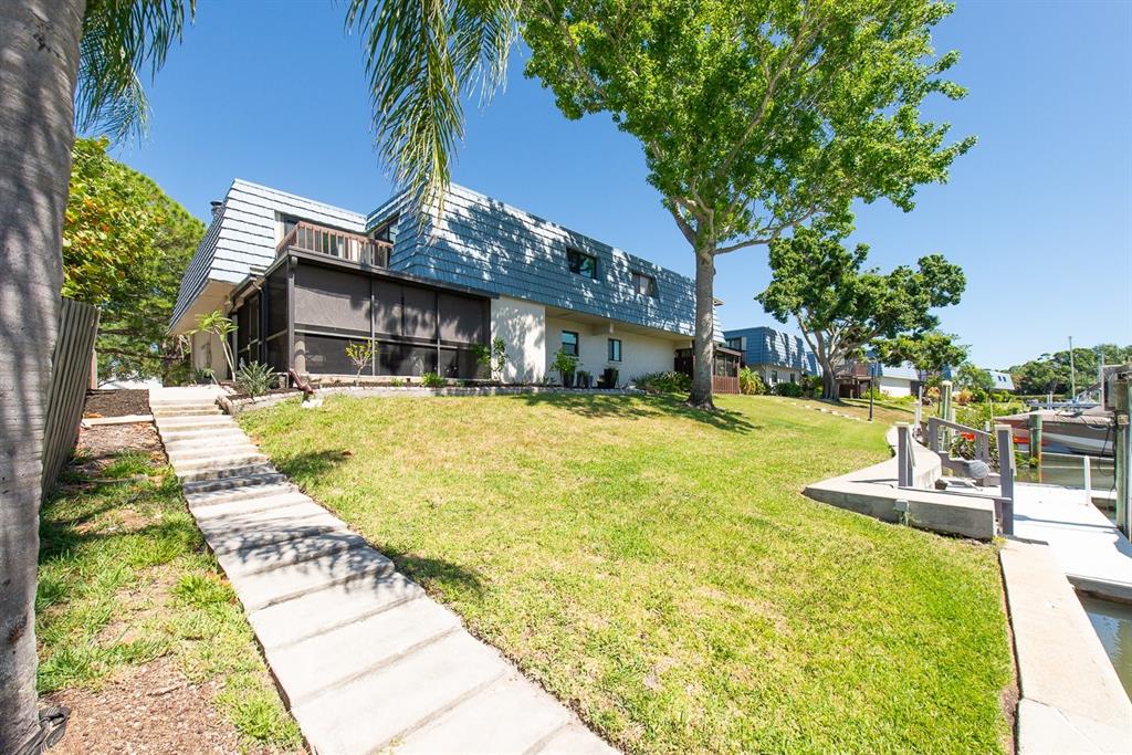 A two-story house with a screened porch and a stone walkway leading to a dock — 9476 TRADEWINDS AVENUE UNIT 9476, SEMINOLE, FL