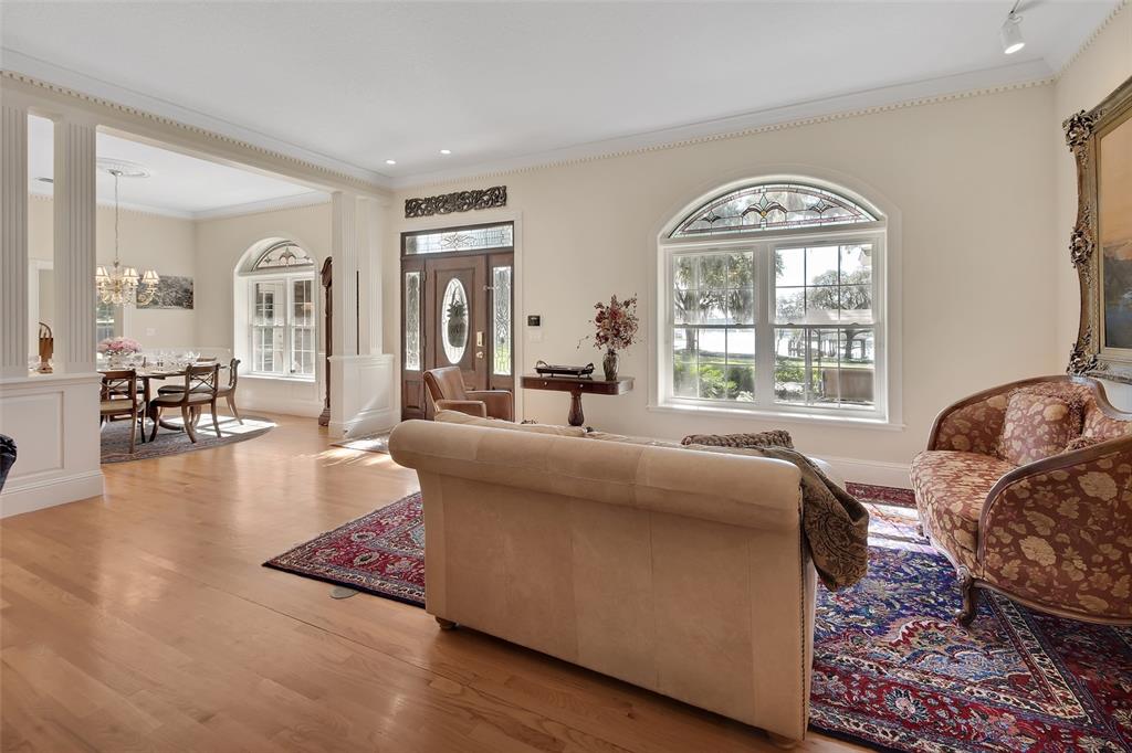 A living room with hardwood floors, a patterned rug, and a view of a dining area — 150 LAKE WINNEMISSETT DRIVE, DELAND, FL
