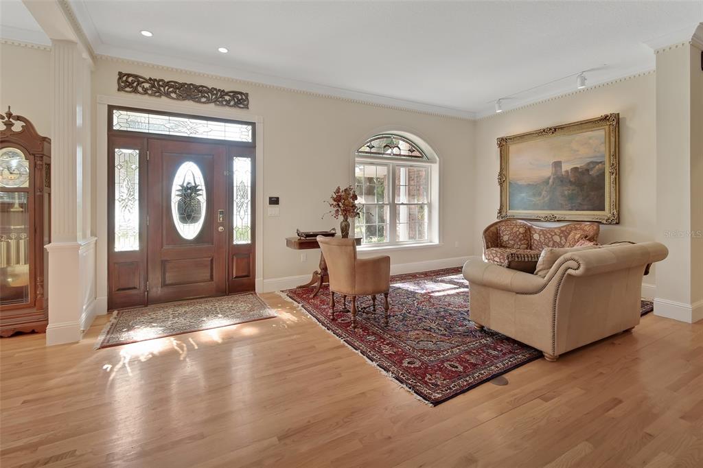 A formal living room features hardwood floors, an ornate area rug, and a wooden front door — 150 LAKE WINNEMISSETT DRIVE, DELAND, FL