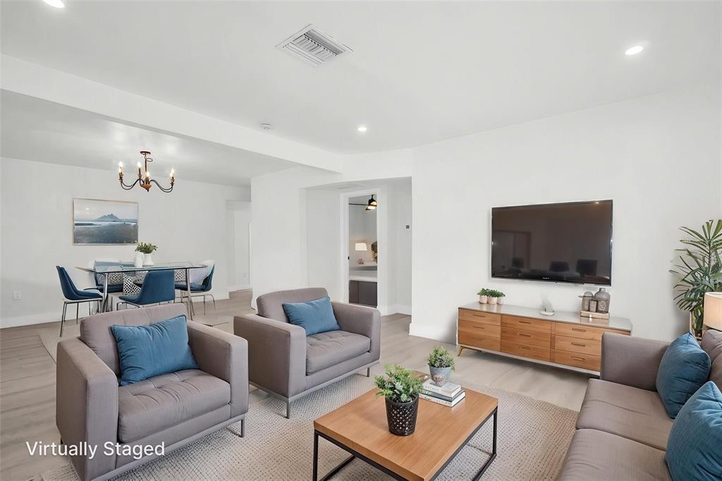 A living room with gray furniture, a wooden media console, and an adjacent dining area — 4000 GROVE STREET S, ST PETERSBURG, FL