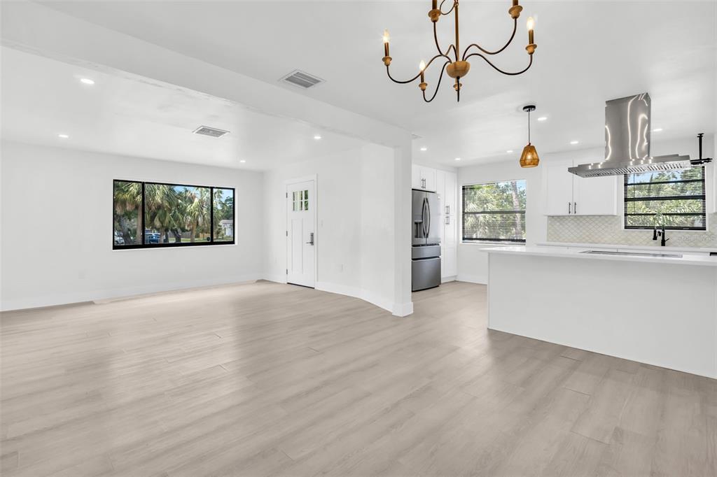 A bright, open-concept living area features light wood-look flooring, white walls, and a modern kitchen — 4000 GROVE STREET S, ST PETERSBURG, FL