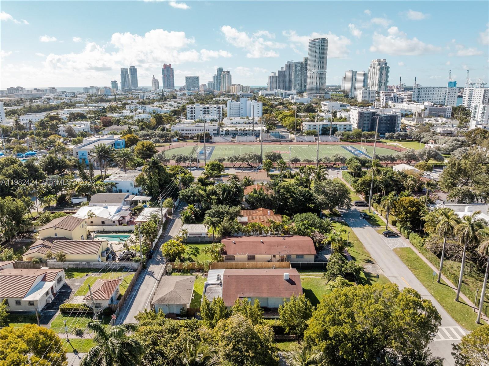 An aerial view shows a residential neighborhood with houses, a football field, and city skyscrapers — 1255 Lenox Ave, Miami Beach FL 33139, MIAMI BEACH, FL
