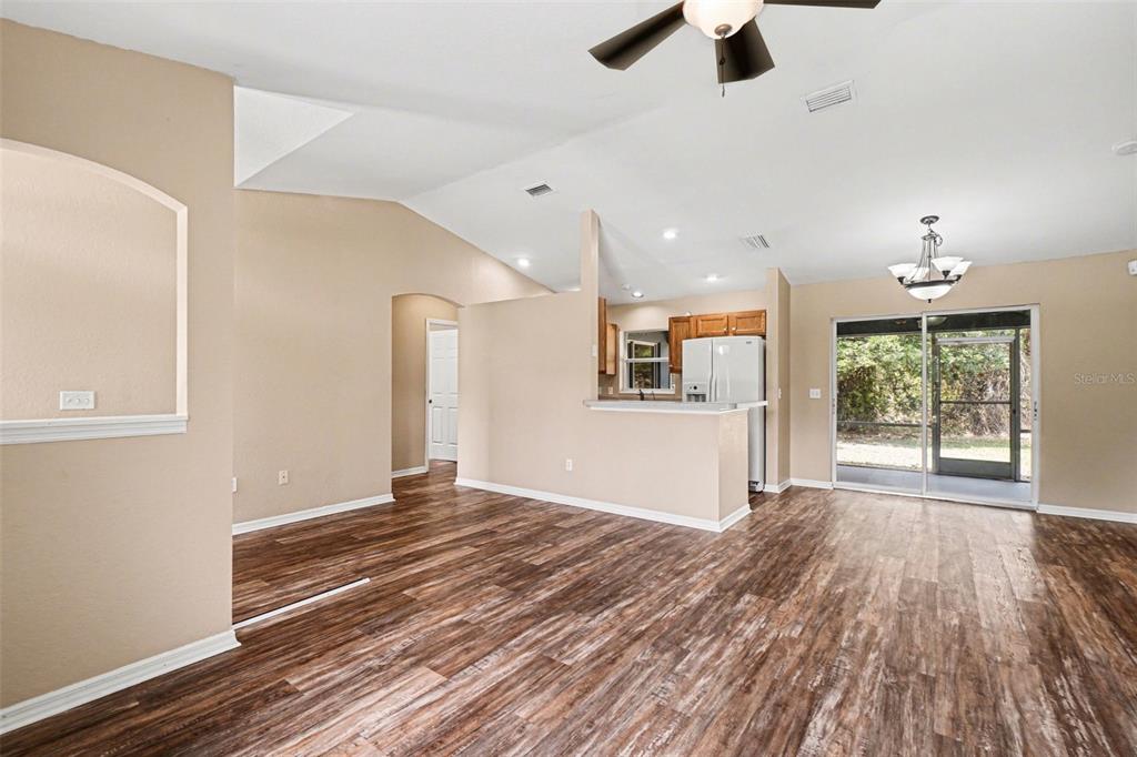 An open-concept living and dining area features wood-look flooring, vaulted ceilings, and a kitchen pass-through — 4431 ANDRIS ST, NORTH PORT, FL