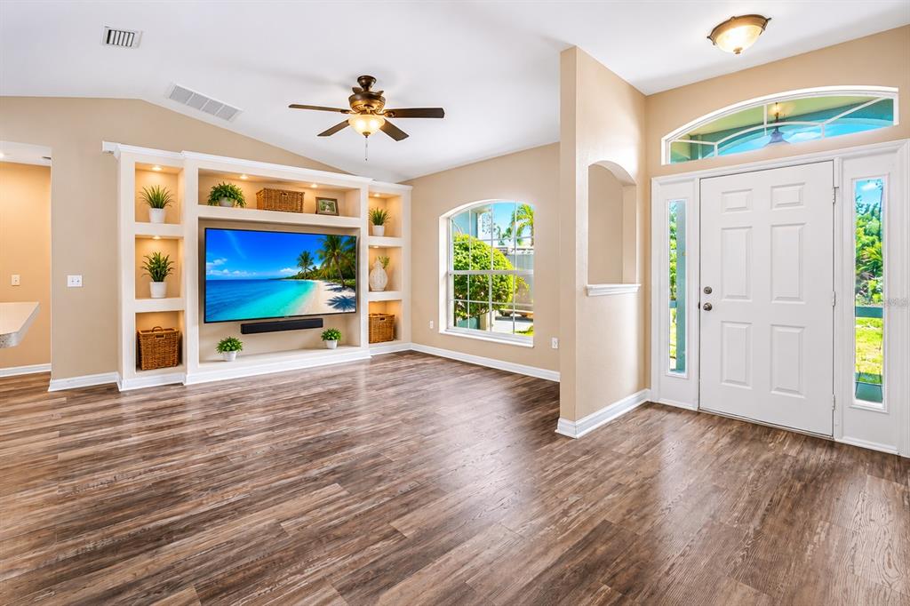 A living room features wood-look flooring, a built-in media center, and a white front door — 4431 ANDRIS ST, NORTH PORT, FL