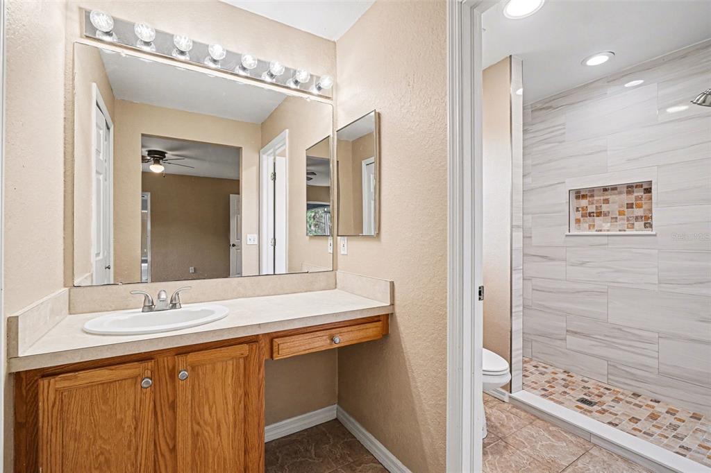 A bathroom features a wooden vanity with a white sink and a tiled walk-in shower — 4431 ANDRIS ST, NORTH PORT, FL
