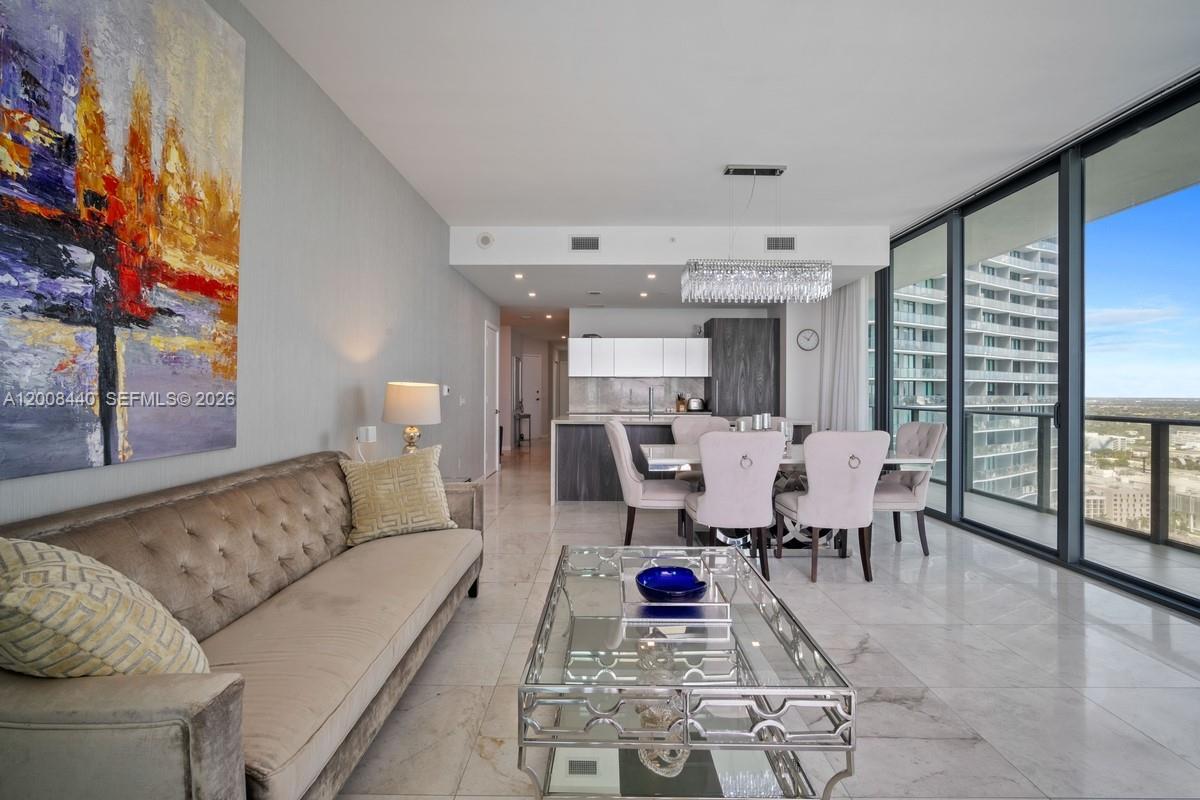 A modern living and dining area features marble floors, a glass coffee table, and balcony views — 480 NE 31 # 2707, Miami FL 33137, MIAMI, FL