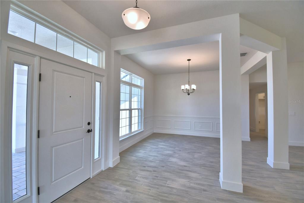 An entryway with light wood-look tile floors leads into a dining area with wainscoting — 5415 WATERSIDE DRIVE, AUBURNDALE, FL
