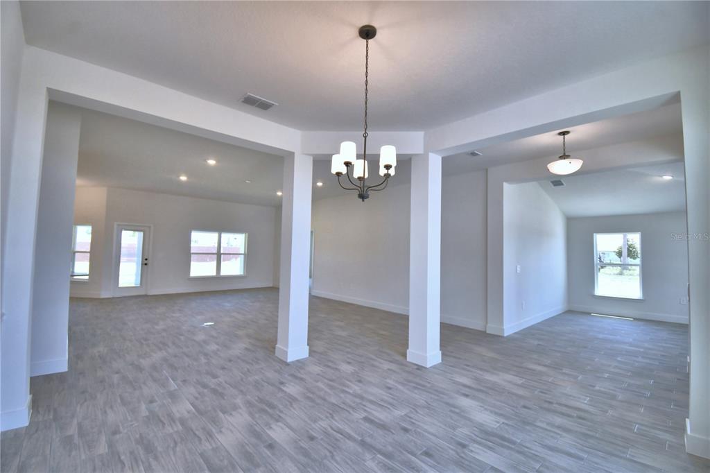 An open-concept living area features white walls, gray wood-look tile flooring, and a central chandelier — 5415 WATERSIDE DRIVE, AUBURNDALE, FL