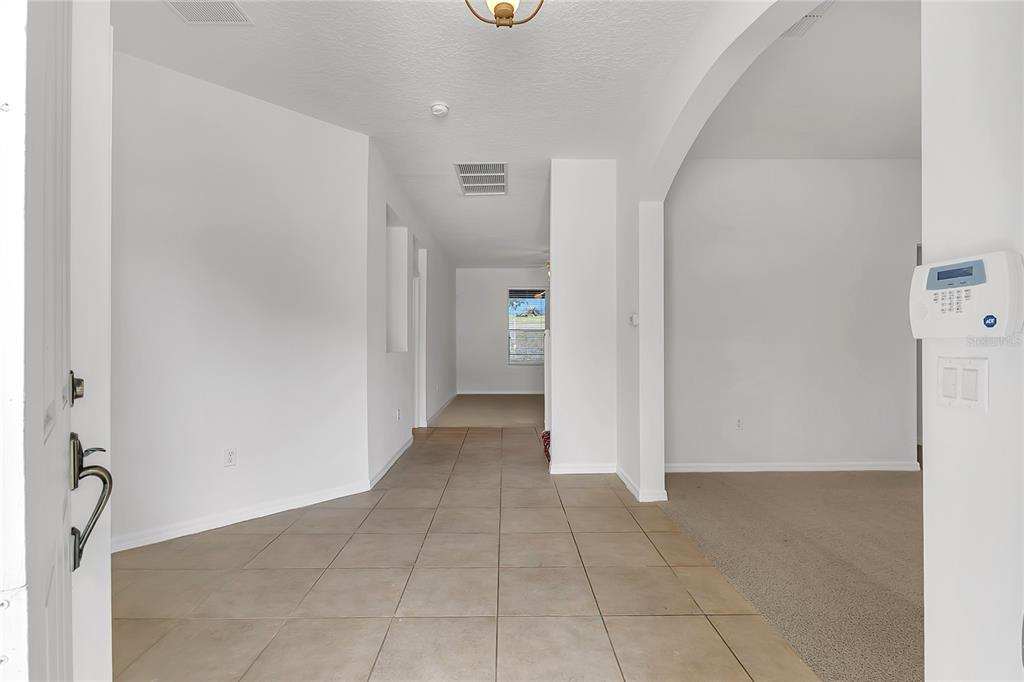 An entryway with tiled flooring leads to a hallway with carpeted rooms beyond — 3323 FAWNWOOD DRIVE, OCOEE, FL
