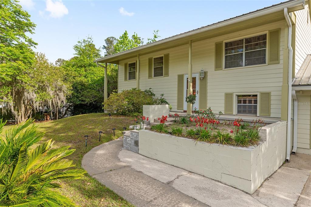 A two-story house with light-colored siding, a raised concrete planter, and a walkway — 505 NW 37TH PLACE, GAINESVILLE, FL