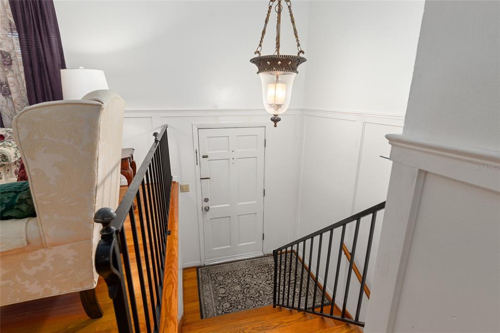 A staircase with black metal railings leads down to a white front door and entryway — 505 NW 37TH PLACE, GAINESVILLE, FL