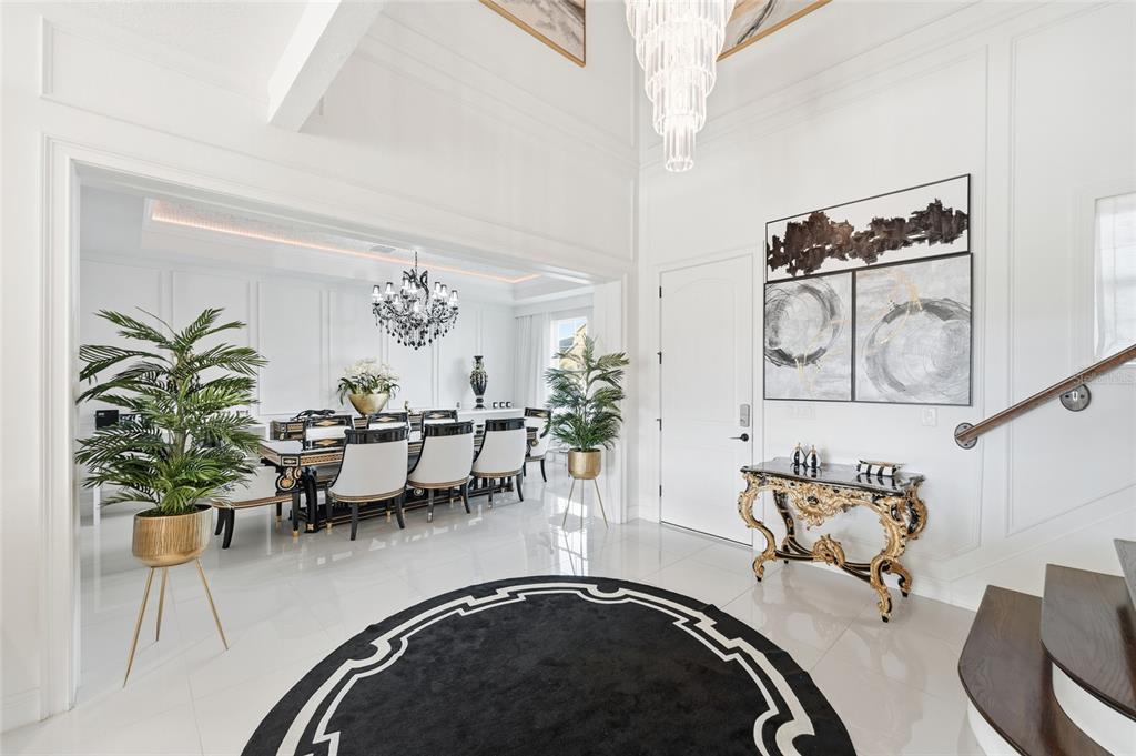 A bright foyer with a black circular rug, gold console table, and adjacent formal dining room — 7969 CHILTON DRIVE, ORLANDO, FL