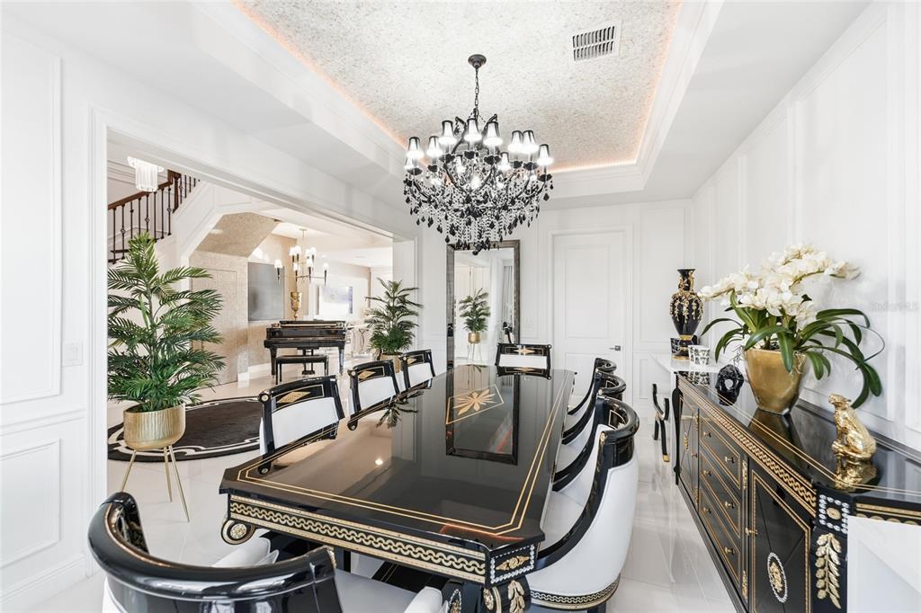 A formal dining room features a black lacquer table, ornate chandelier, and white paneled walls — 7969 CHILTON DRIVE, ORLANDO, FL