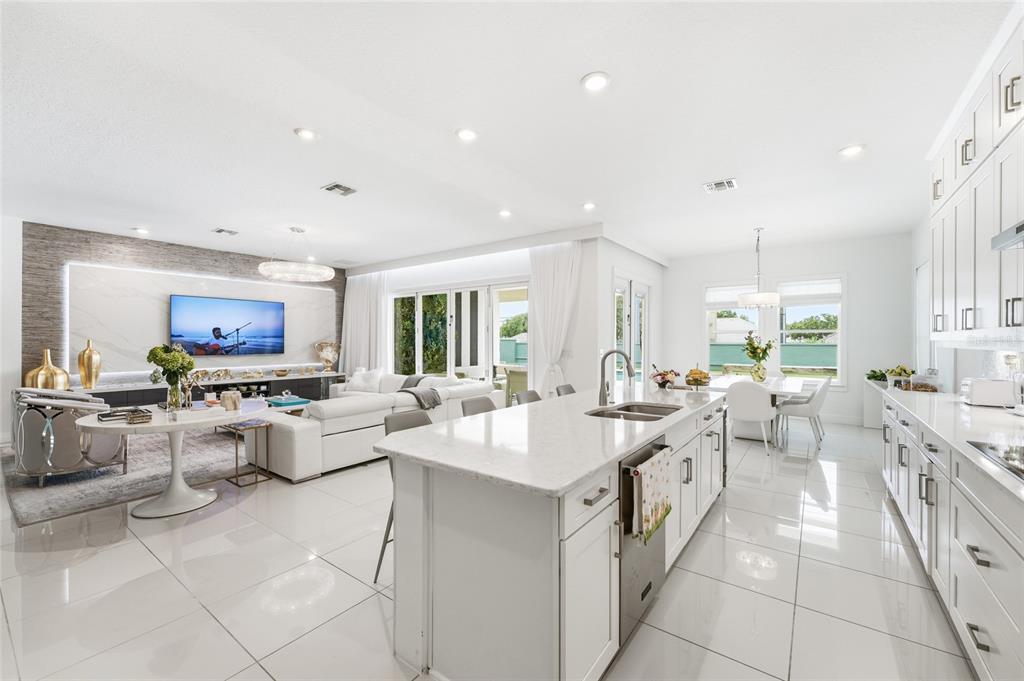 An open-concept kitchen and living area with white cabinetry, a large island, and tile flooring — 7969 CHILTON DRIVE, ORLANDO, FL