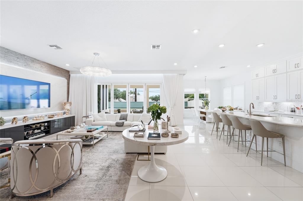 A bright, open-concept living room and kitchen featuring white tile floors and modern furniture — 7969 CHILTON DRIVE, ORLANDO, FL