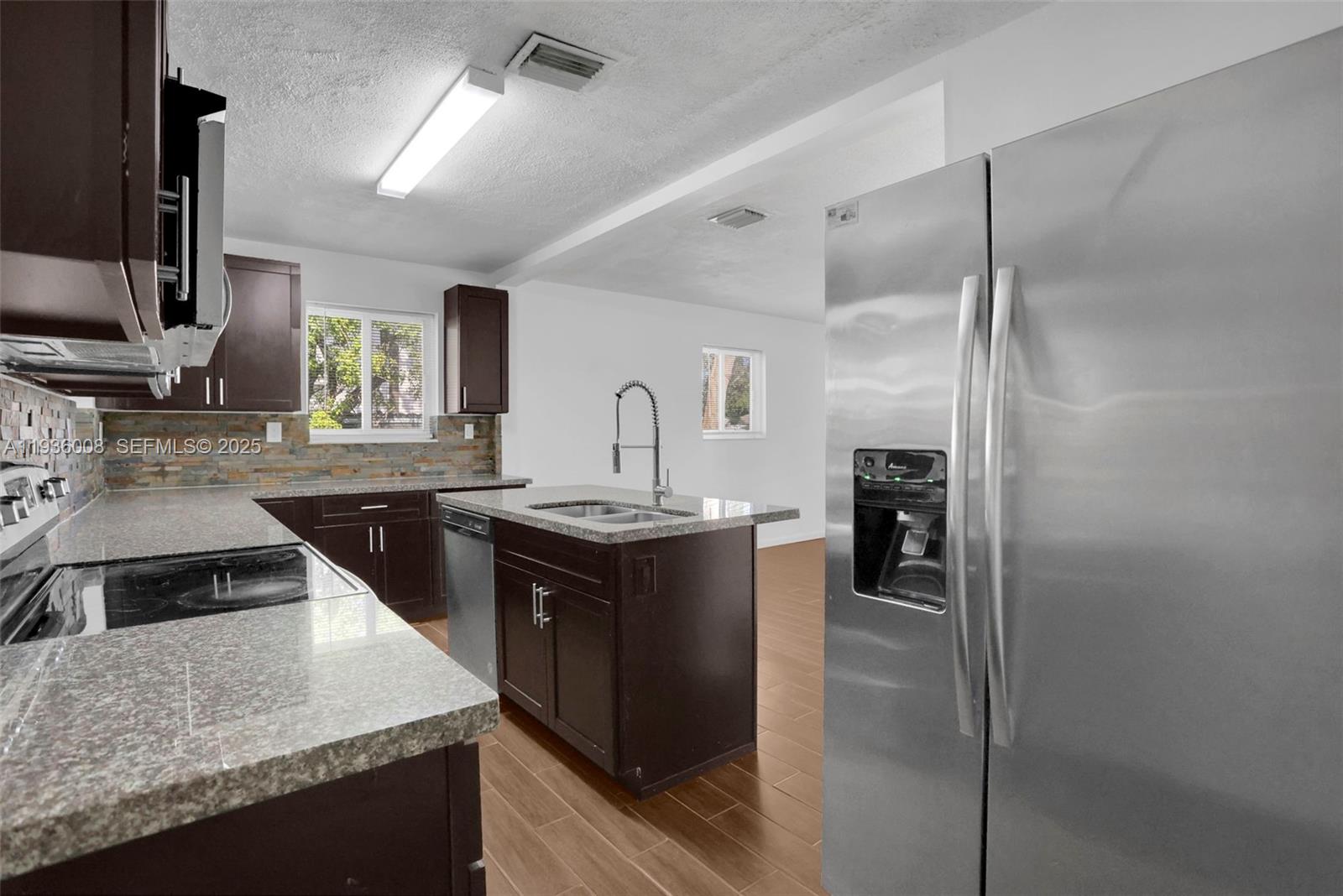 A kitchen features dark wood cabinets, granite countertops, stainless steel appliances, and wood-look tile flooring — 510 N 69th Ave # 0, Hollywood FL 33024, HOLLYWOOD, FL
