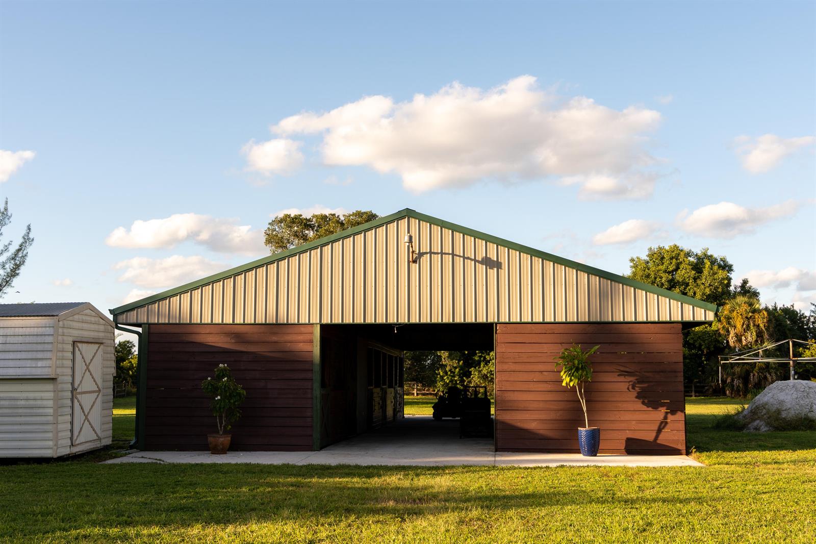 A brown and beige barn with an open center aisle stands on a grassy lawn — 14279 43rd Road N, FL 33470, FL