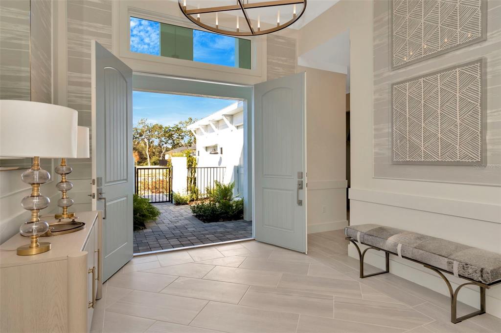 An open entryway features light blue double doors, tile flooring, and a bench — 12714 IVORY TUSK LANE, SPRING HILL, FL