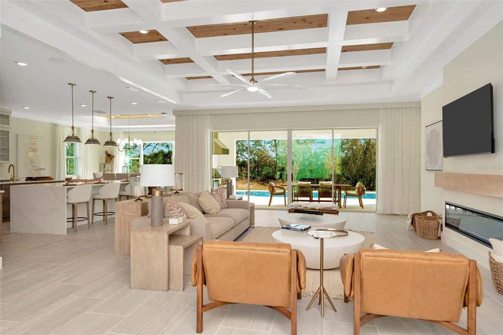 An open-concept living room features a coffered wood ceiling, fireplace, and sliding glass doors — 12714 IVORY TUSK LANE, SPRING HILL, FL