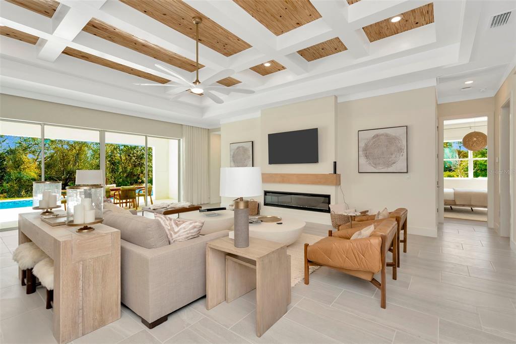 A modern living room features a coffered wood ceiling, fireplace, and sliding doors to a pool — 12714 IVORY TUSK LANE, SPRING HILL, FL