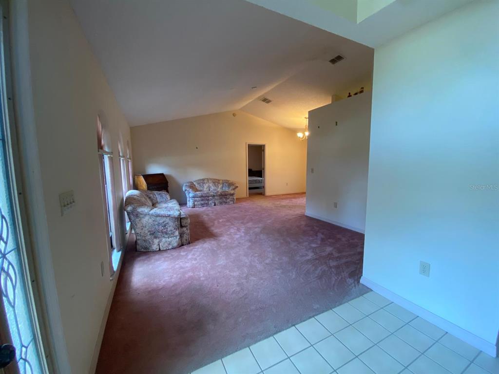 A living room features mauve carpeting, vaulted ceilings, and two floral-patterned sofas — 508 BROKENSHIRE DRIVE, DEBARY, FL