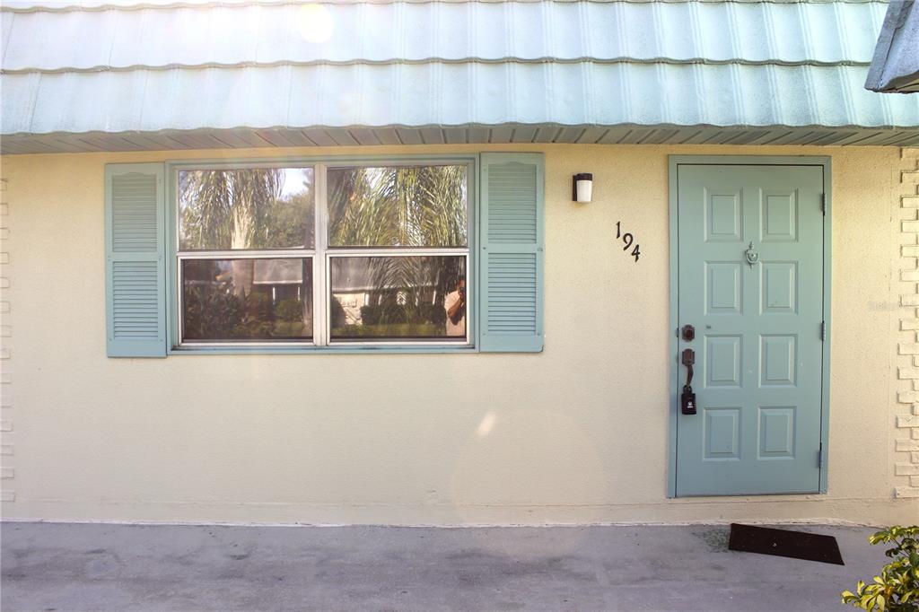 The exterior of a home features a light blue door, a window with shutters, and address numbers — 101 CAMBRIDGE TRAIL UNIT 194, SUN CITY CENTER, FL