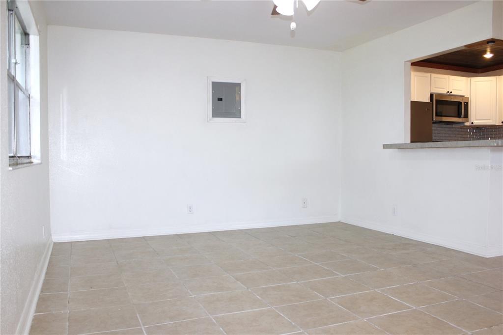 An empty room with white walls, tile flooring, and a view into the kitchen — 101 CAMBRIDGE TRAIL UNIT 194, SUN CITY CENTER, FL