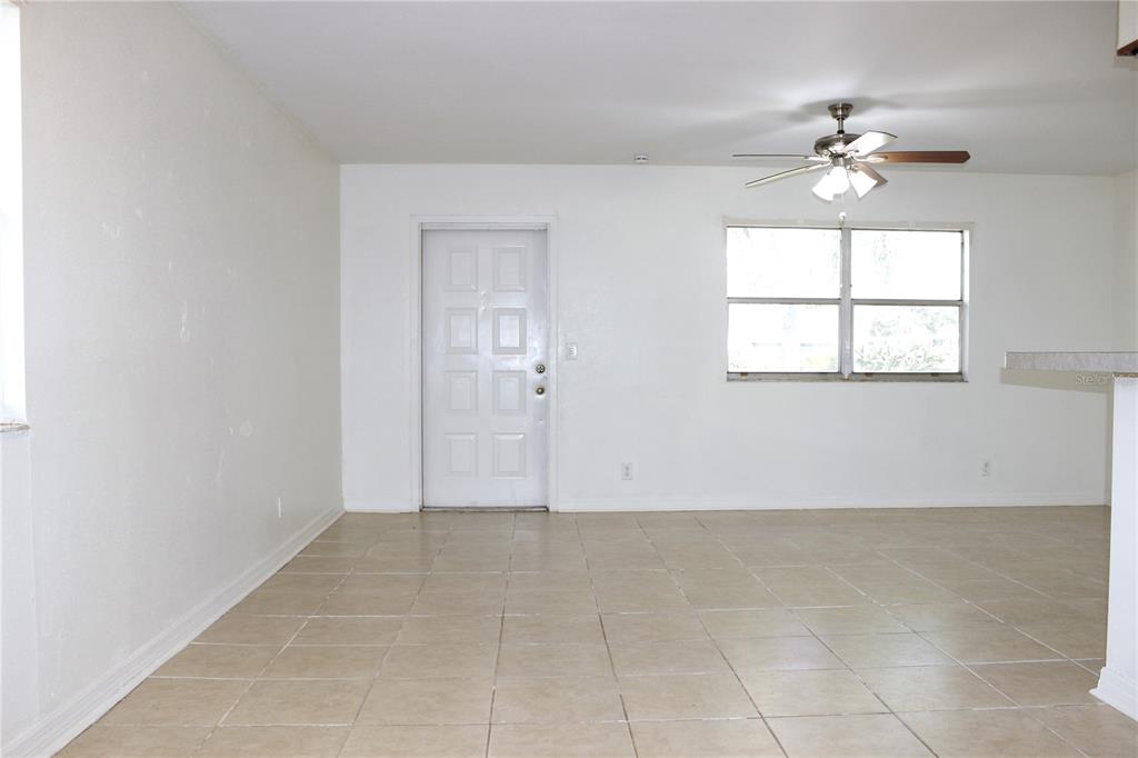 A room with white walls, tile flooring, a ceiling fan, and a white front door — 101 CAMBRIDGE TRAIL UNIT 194, SUN CITY CENTER, FL