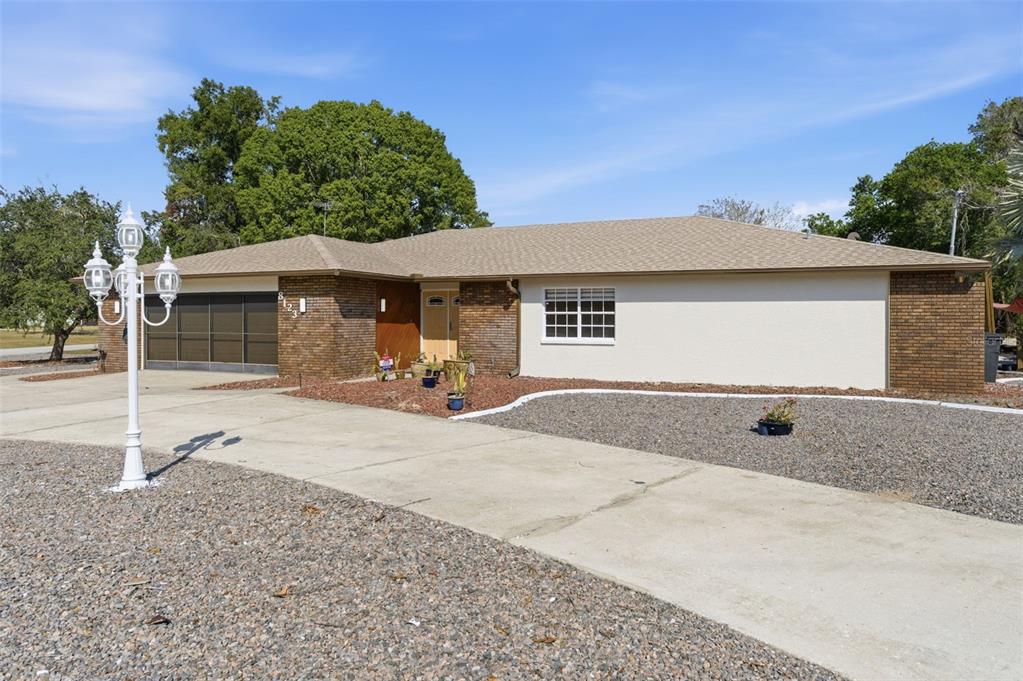 A single-story brick and stucco house with a garage and a gravel front yard — 8123 RIVER COUNTRY DRIVE, WEEKI WACHEE, FL