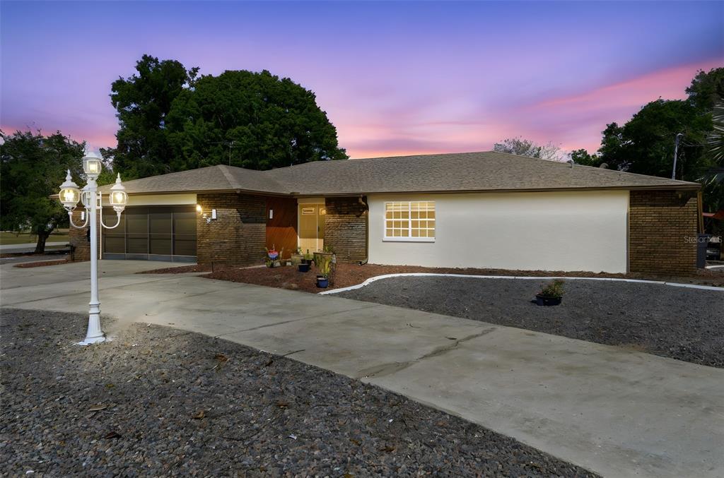 A single-story house with a brick and stucco exterior, a concrete driveway, and a lamp post — 8123 RIVER COUNTRY DRIVE, WEEKI WACHEE, FL
