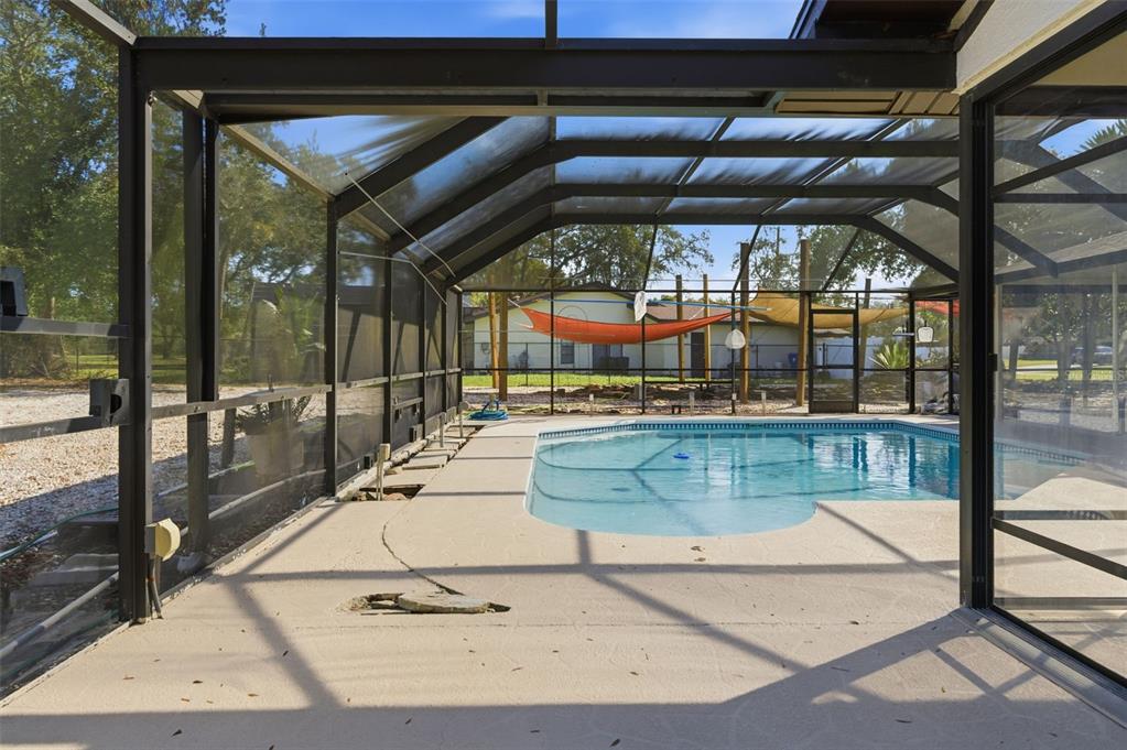 A screened-in pool enclosure with a concrete deck and a view of the backyard — 8123 RIVER COUNTRY DRIVE, WEEKI WACHEE, FL