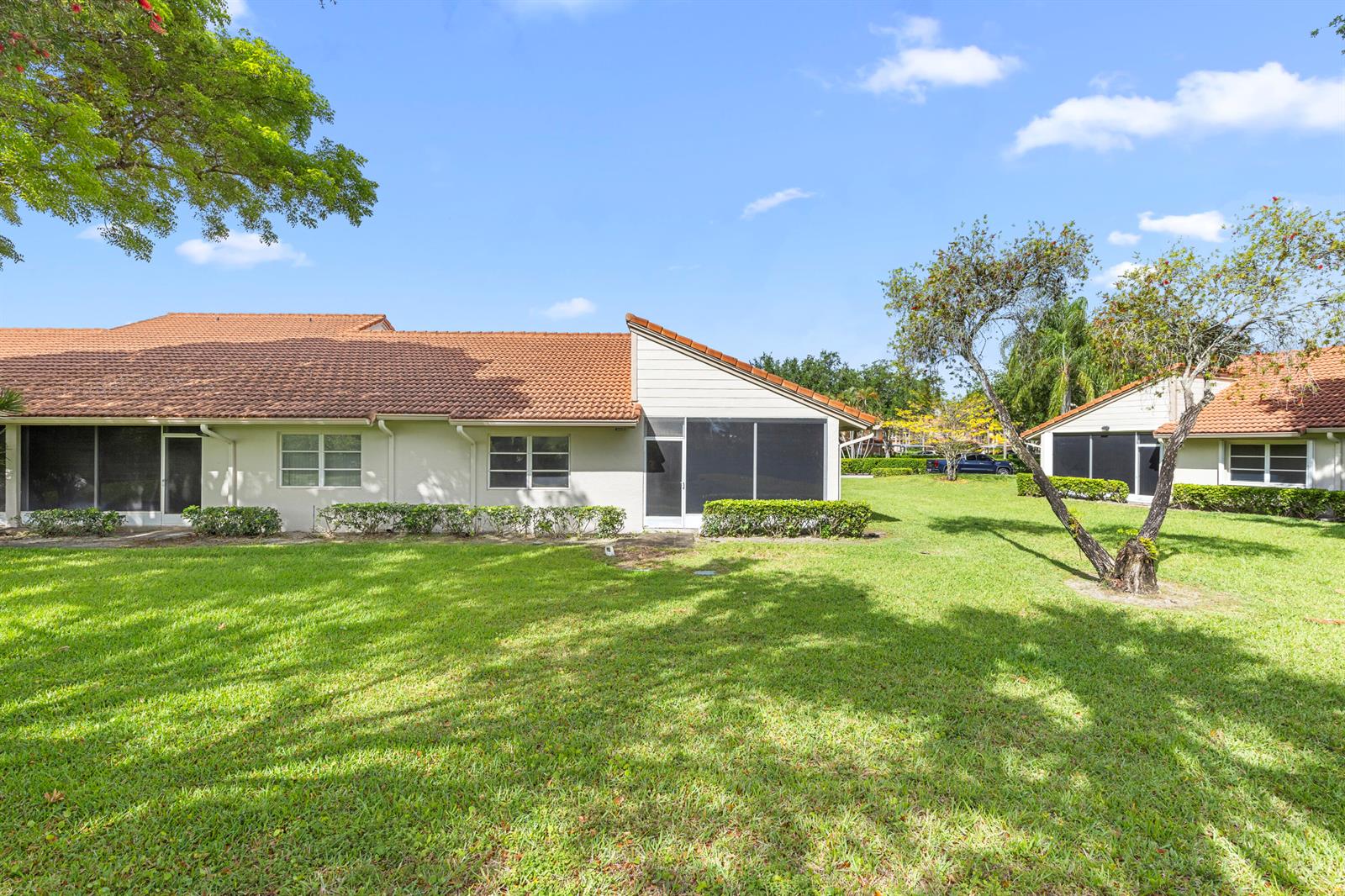 The exterior of a single-story residential building features a tiled roof and screened-in patios — 9760 Summerbrook Terrace # A, Boynton Beach FL 33437, BOYNTON BEACH, FL