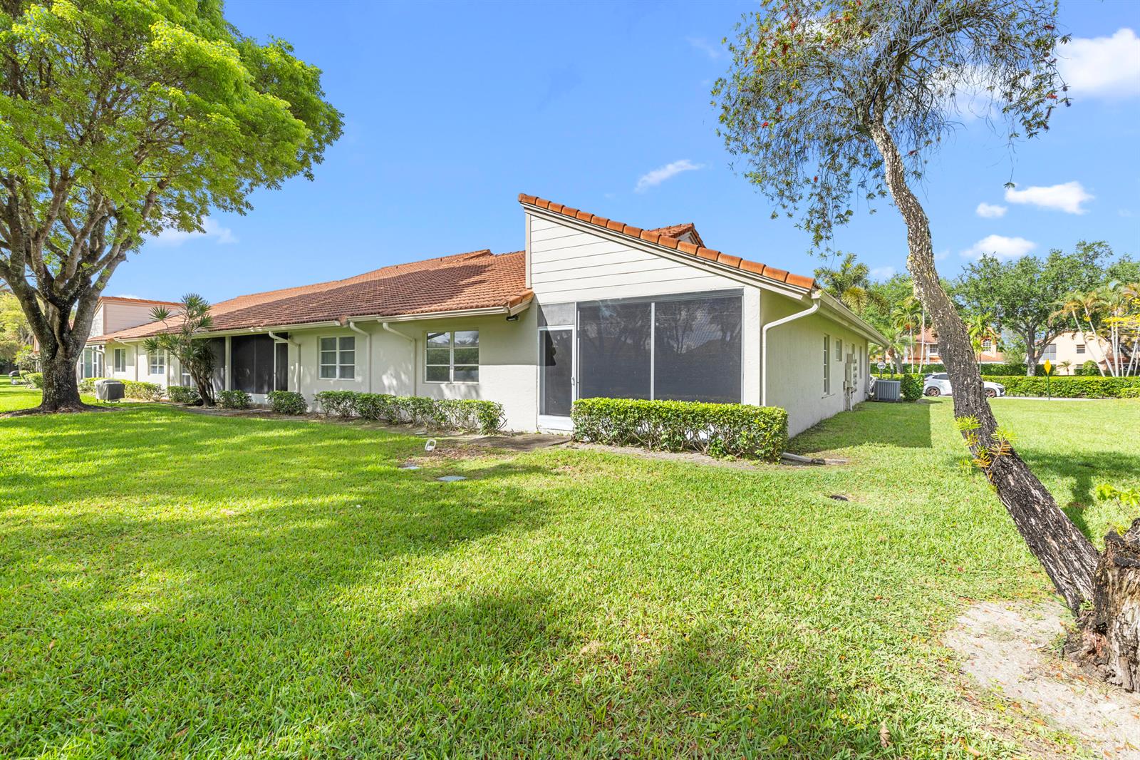 A single-story house with a tiled roof, screened-in patio, and surrounding lawn under blue skies — 9760 Summerbrook Terrace # A, Boynton Beach FL 33437, BOYNTON BEACH, FL
