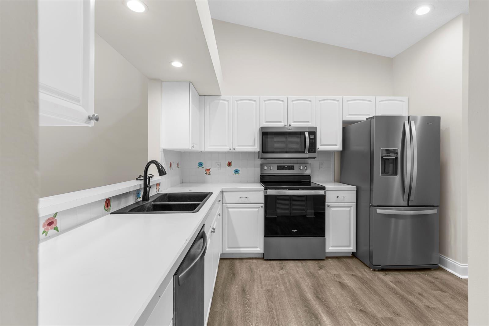 A kitchen features white cabinets, stainless steel appliances, a black sink, and wood-look flooring — 9760 Summerbrook Terrace # A, Boynton Beach FL 33437, BOYNTON BEACH, FL