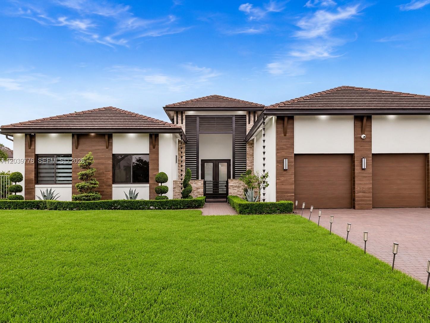 A modern single-story house features a tiled roof, wood-paneled accents, and a two-car garage — 4980 SW 159th Ave, Southwest Ranches FL 33331, SOUTHWEST RANCHES, FL