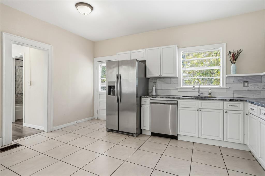 A bedroom features a bed with white bedding, two black ottomans, and four large windows — 4026 4TH AVENUE S, ST PETERSBURG, FL