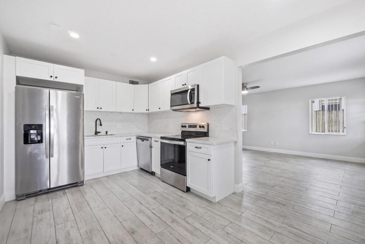 A kitchen with white cabinets, stainless steel appliances, and light wood-look tile flooring — 712 NE 10th Avenue, Pompano Beach FL 33060, POMPANO BEACH, FL
