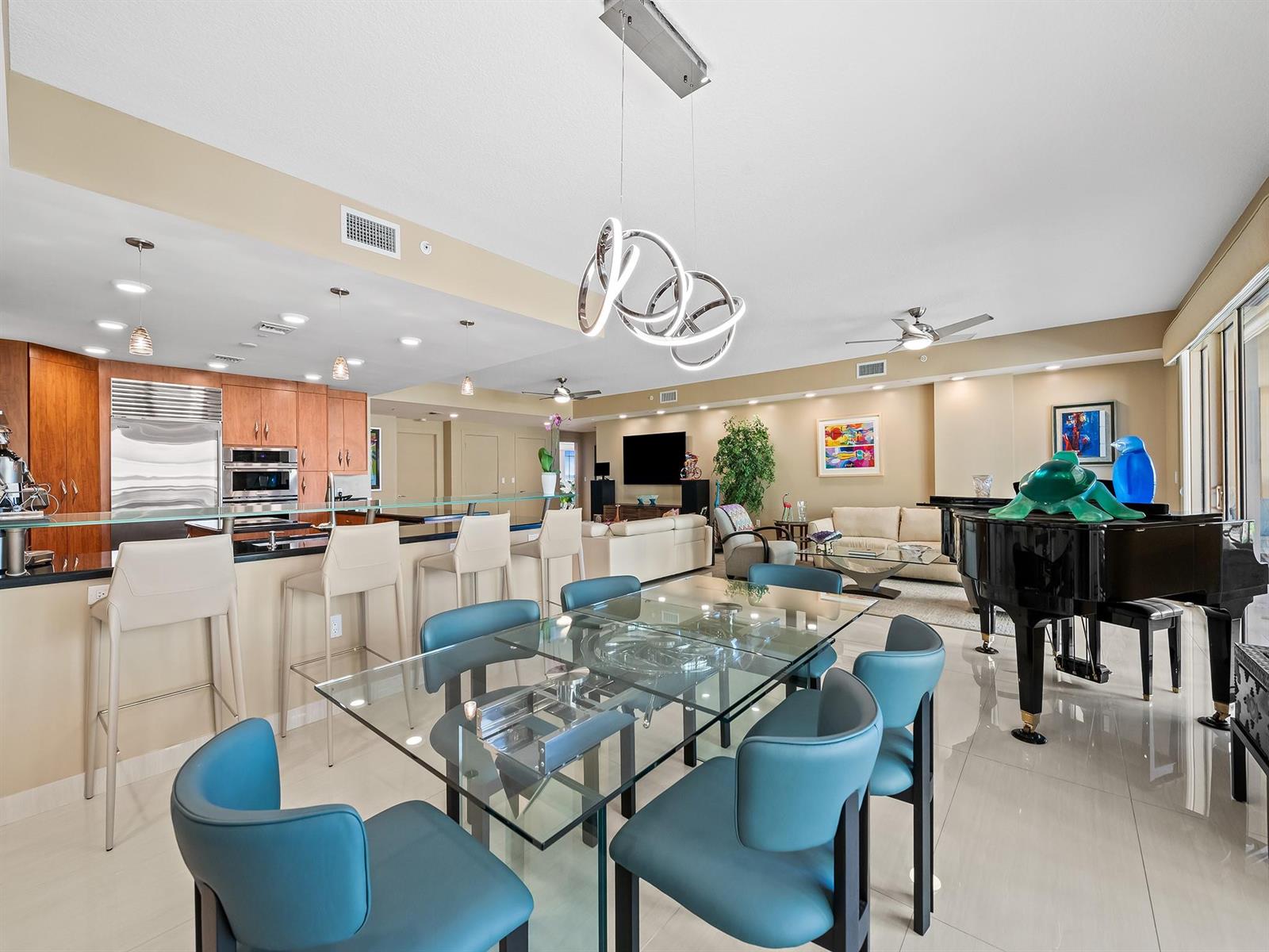 A modern open-concept living and dining area features a glass table, piano, and kitchen island — 3415 N Ocean Drive # 505, Hollywood FL 33019, HOLLYWOOD, FL