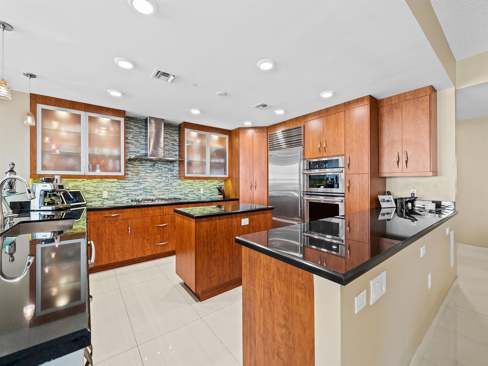 A kitchen features wood cabinetry, black granite countertops, stainless steel appliances, and a tiled floor — 3415 N Ocean Drive # 505, Hollywood FL 33019, HOLLYWOOD, FL