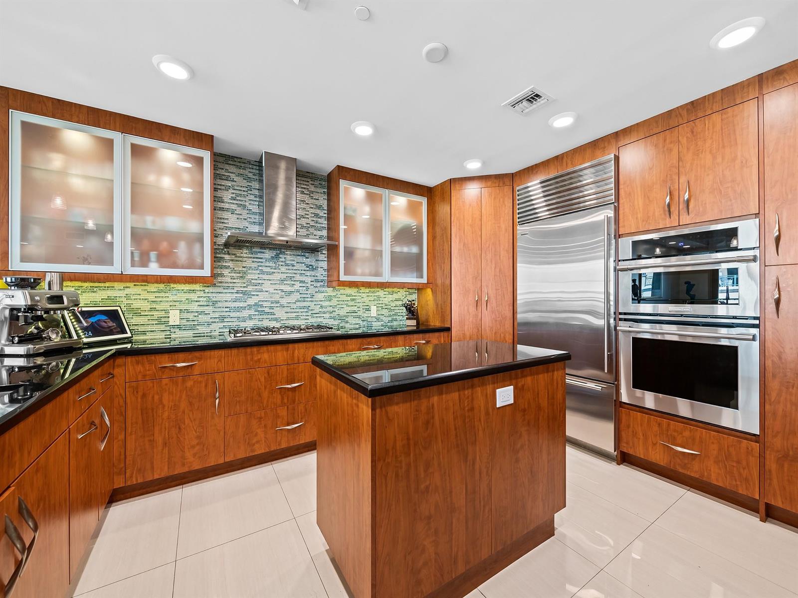 A modern kitchen features wood cabinets, stainless steel appliances, a black island, and tile flooring — 3415 N Ocean Drive # 505, Hollywood FL 33019, HOLLYWOOD, FL