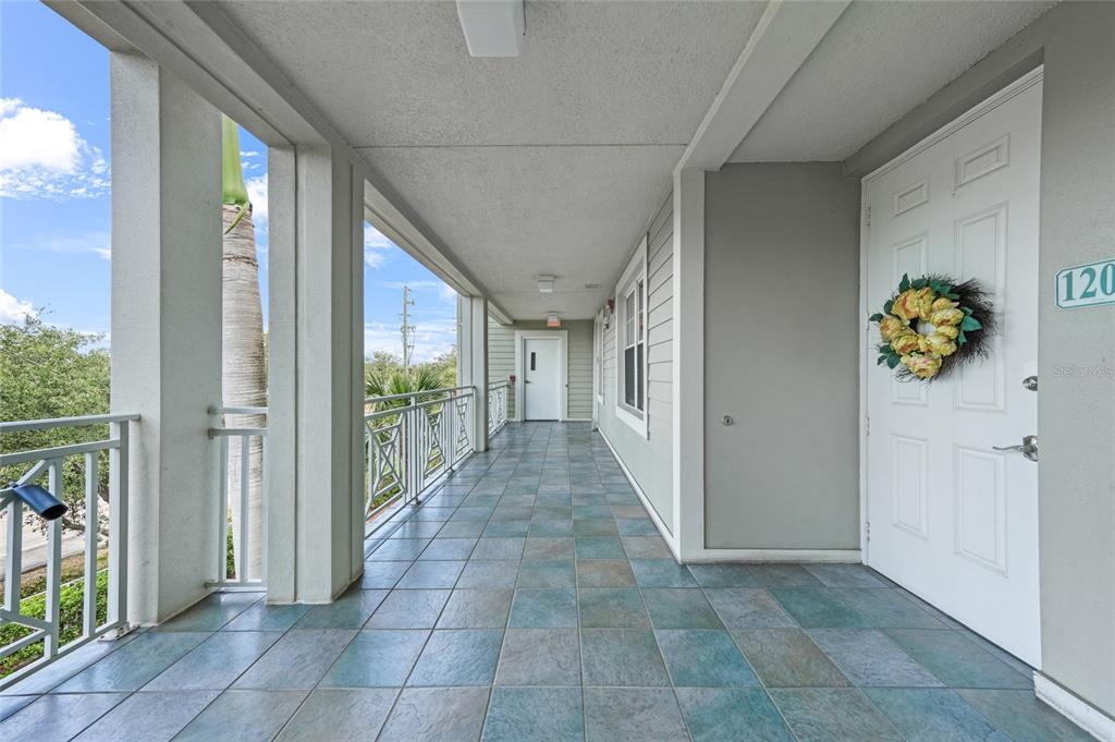 An outdoor tiled walkway leads to a white front door marked with the number 120 — 5114 MELBOURNE STREET UNIT A202, PUNTA GORDA, FL