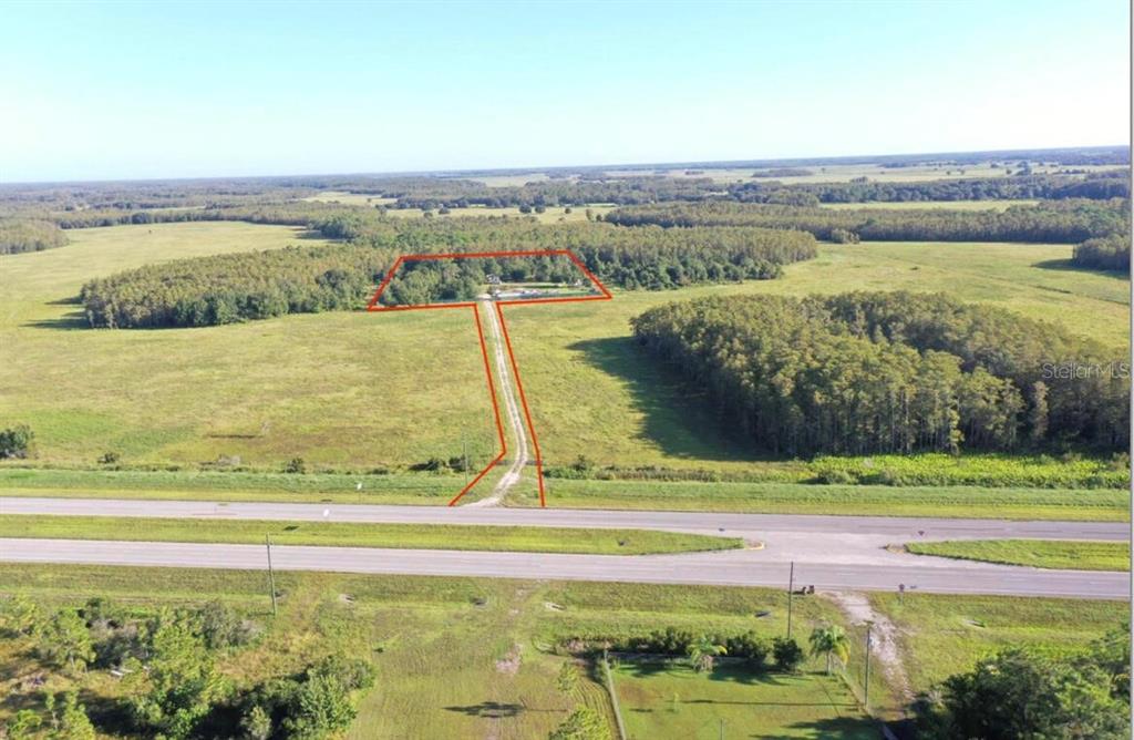 An aerial view shows a rural property with a long driveway leading to a wooded lot — 9699 E IRLO BRONSON MEMORIAL HIGHWAY, ST CLOUD, FL