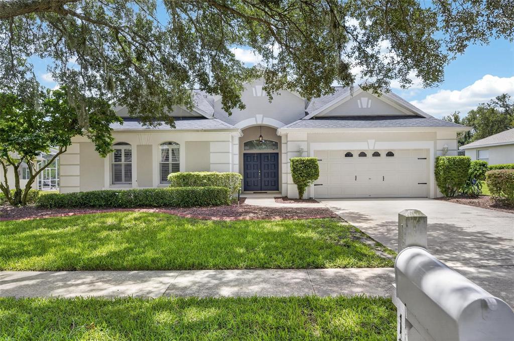 A single-story house with a blue front door, a two-car garage, and a manicured lawn — 12419 RIVERGLEN DRIVE, RIVERVIEW, FL