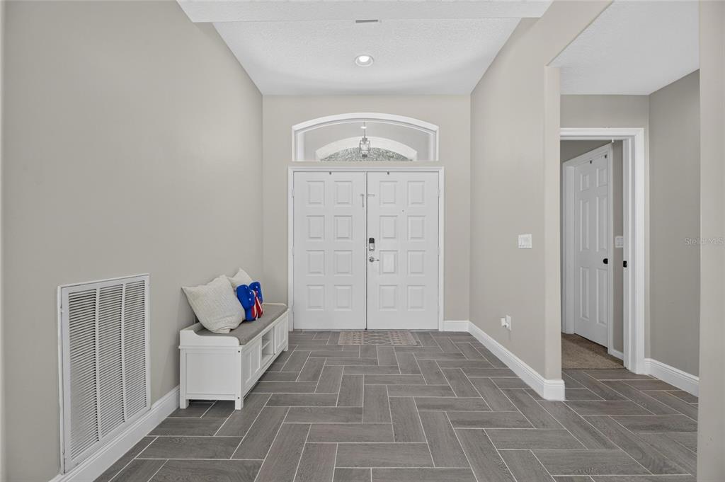 An entryway features gray herringbone tile flooring, a white storage bench, and double front doors — 12419 RIVERGLEN DRIVE, RIVERVIEW, FL