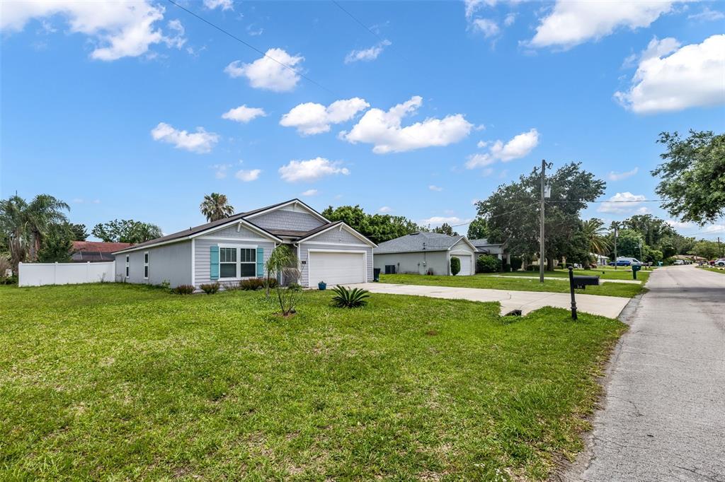 A single-story house with light gray siding and a two-car garage sits on a lawn — 54 PATCHOGUE LANE, PALM COAST, FL