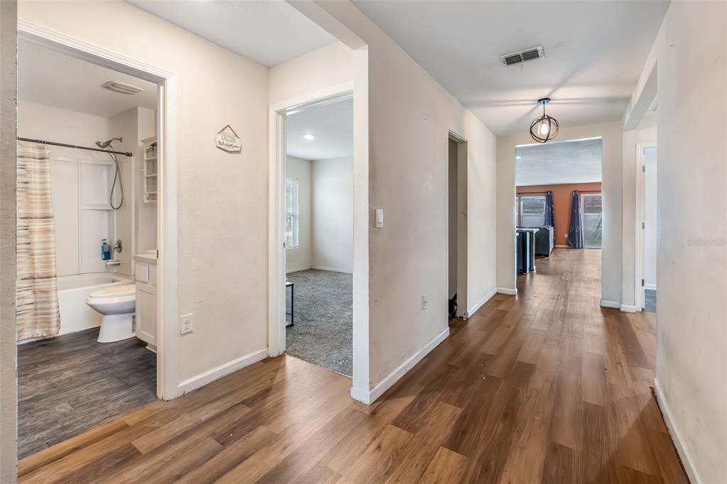 A hallway with wood-look flooring leads to a living area, a bathroom, and a bedroom — 54 PATCHOGUE LANE, PALM COAST, FL