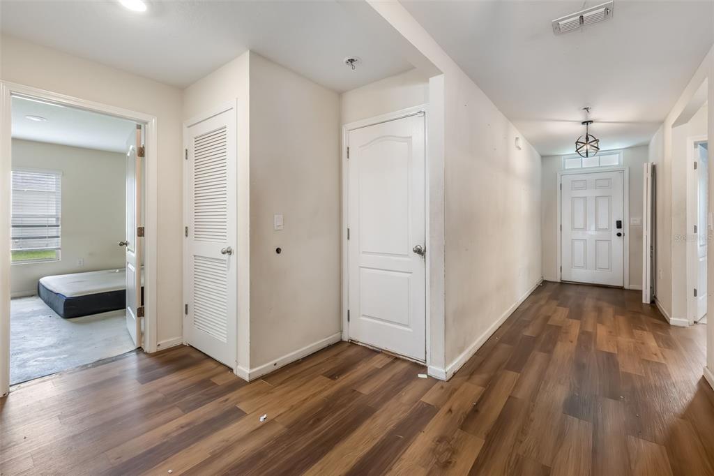 An interior hallway features wood-look flooring, white doors, and a view into an adjacent bedroom — 54 PATCHOGUE LANE, PALM COAST, FL